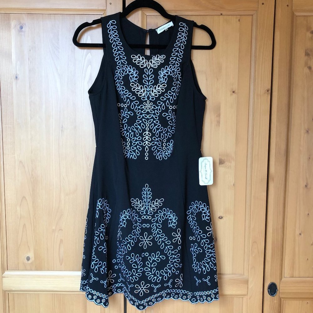 Black dress with decorative embroidered eyelet detail.